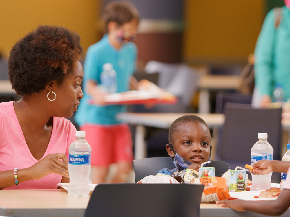 Grown-up and child sitting at a table in the Food Court.